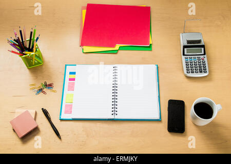 Modern creative workspace made of a flat wooden table, color pencils, a notebook,  coffee a smartphone and other objects Stock Photo