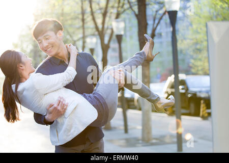 Young man carrying girlfriend in arms Stock Photo