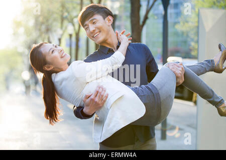 Young man carrying girlfriend in arms Stock Photo