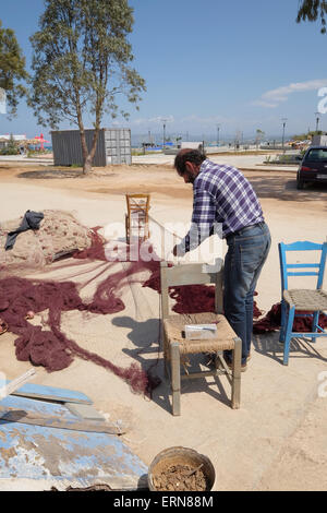 Cretan fisherman mending nets on quayside at Georgioupoli Crete Greece Stock Photo