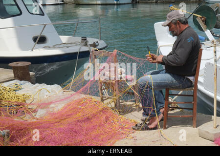 Cretan fisherman mending nets on quayside at Georgioupoli Crete Greece Stock Photo