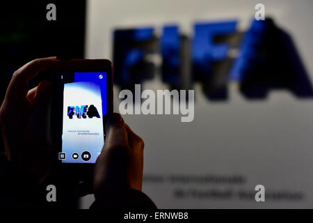 A passerby is taking a smartphone picture of the FIFA logo at the entrance sign to the organisation's headquarters in Zurich, on the night Sepp Blatter announced his resignation as FIFA president. Stock Photo
