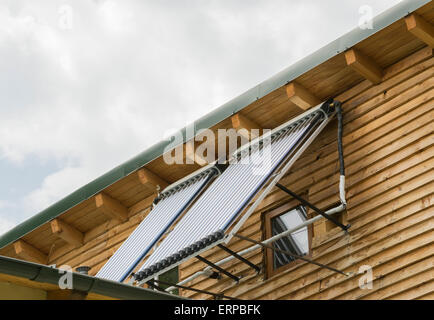 Two panels mounted side by side on the exterior wall of a house for water heating using solar energy conversion Stock Photo