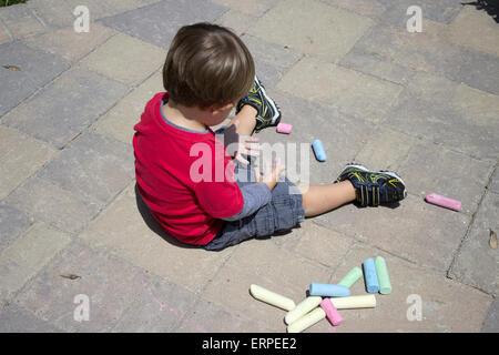 Little boy playing with chalk on cement pavers Stock Photo