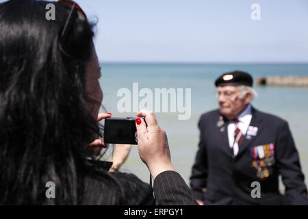 A veteran of WW2 has his photo taken on D-Day 71st Anniversary, Normandy France. Services and musical parades are held in Arromanche to mark  the 71st anniversary of the D-Day landings. Veterans and the public enjoy the day at Arromanche, site of the Mulberry Harbour and British D-Day landing sites. Re-enactment groups in period uniforms displayed vintage WW2 vehicles to a back drop of 1940's era music. Stock Photo