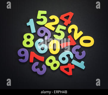 Wooden numbers on black background, various colors, accentuated center of an image. Stock Photo