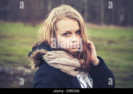 Closeup outdoor portrait of beautiful blond Caucasian teenage girl in a spring forest, tonal photo filter effect, old style Stock Photo