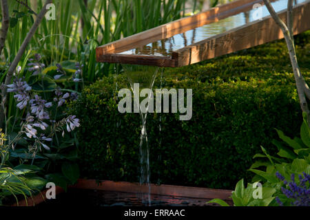Water flowing over a wooden rill into a pond in The Vestra Wealth Garden at The Hampton Court Flower Show,2014 Stock Photo