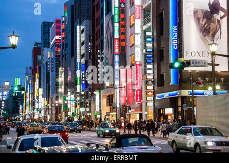 The Ginza at night. View along the busy street with traffic blocking the road, people on the pavement and illuminated signs and buildings. Stock Photo