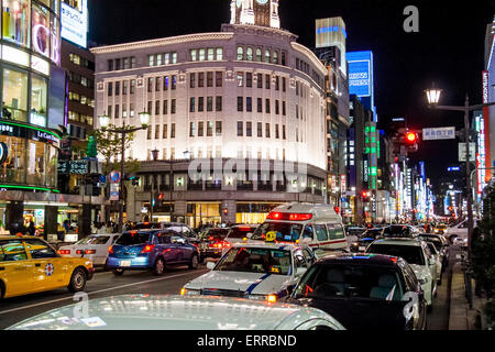 Night on the Ginza 4-chome Intersection, view along street with the illuminated Wako department store, while in foreground, traffic and street. Stock Photo