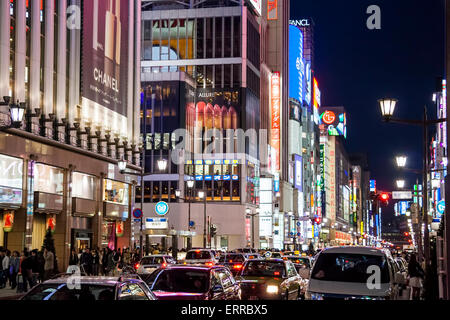 The Ginza at night. View along the busy street with traffic blocking the road, people on the pavement and illuminated signs and buildings. Stock Photo