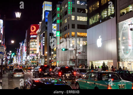 The Ginza at night. View along traffic filled street with the Apple Store in foreground and in background the Sanai building on the Ginza crossing. Stock Photo