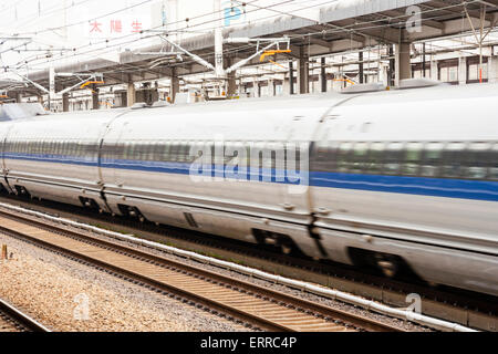 A Japanese 500 series Shinkansen, Nozomi bullet train, passing through a station at full speed. Station in focus, train subject to blurred motion. Stock Photo