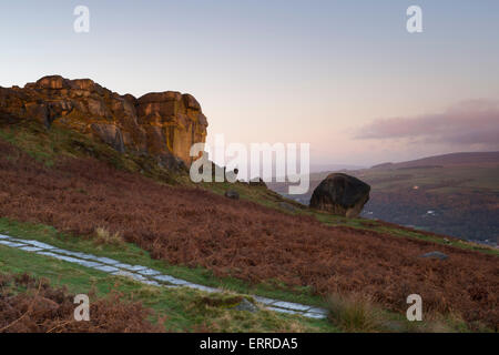 Scenic rural landscape of pink & blue sky at sunrise over high rocky upland outcrop - Cow and Calf Rocks, Ilkley Moor, West Yorkshire, England, UK.