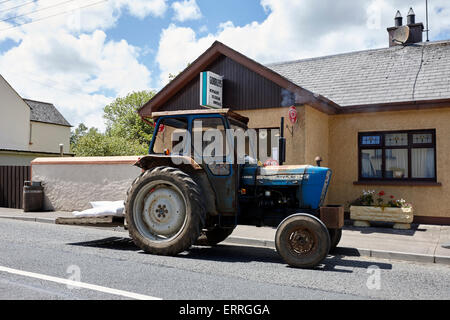 old tractor parked outside a local shop in a small village in rural ireland emyvale monaghan Stock Photo