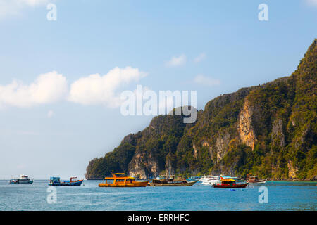 Motor boat with passengers moving on blue tropical Thailand sea near big rocks island