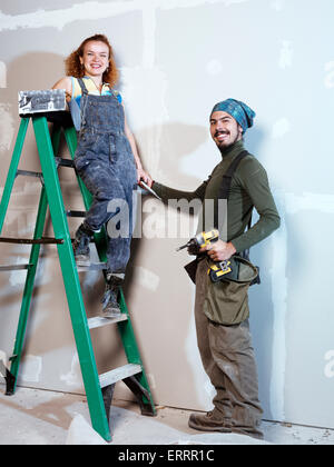 Portrait of a smiling young couple renovating, patching up drywall Stock Photo