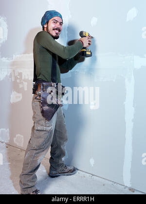 Portrait of a smiling young man contractor worker mounting drywall renovating interior Stock Photo