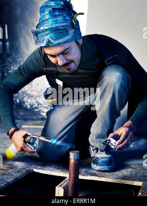 Portrait of man contractor worker with a blow torch capping a pipe doing plumbing Stock Photo