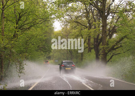Car splashing through large puddle on country road in Scotland after heavy rain Stock Photo