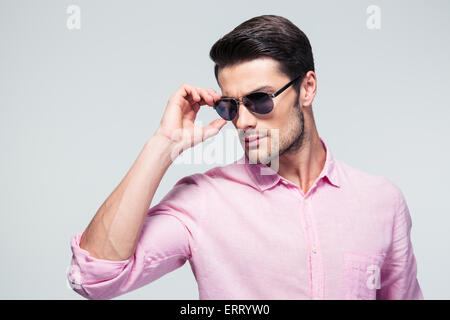 Handsome young man in sunglasses and shirt over gray background Stock Photo