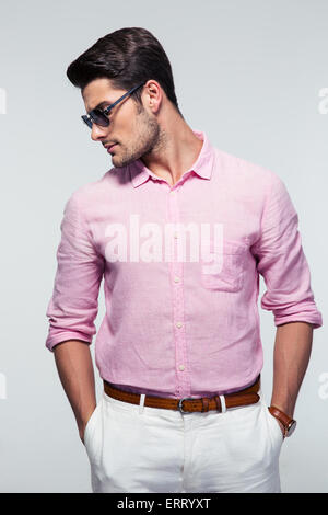 Handsome young man in glasses looking away over gray background Stock Photo