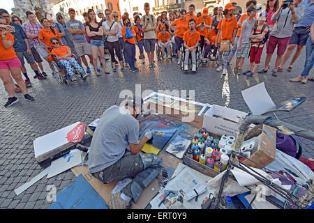 An artist completing a spray painting ion front of an audience of tourists & handicapped children at Piazza Navona in Rome, Italy Stock Photo