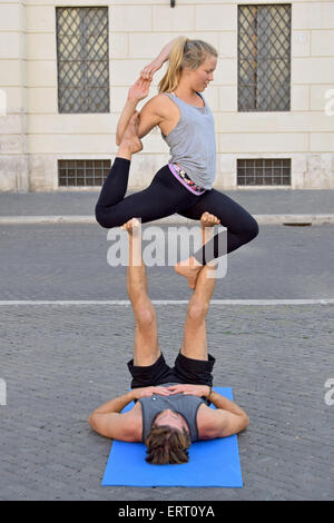 An athletic fit couple do acro yoga exercises at Piazza Navona in Rome Italy. Stock Photo