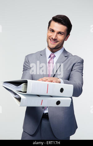 Happy confident businessman giving folders at camera over gray background Stock Photo
