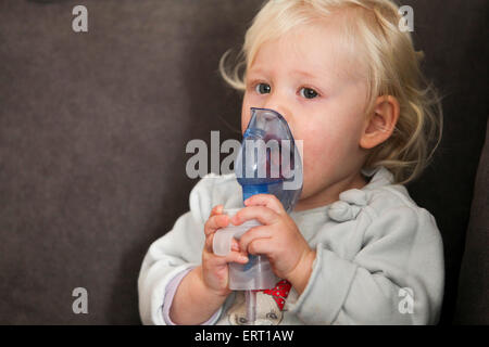 Baby uses an inhalation mask by herself Stock Photo