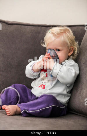 Baby uses an inhalation mask by herself Stock Photo