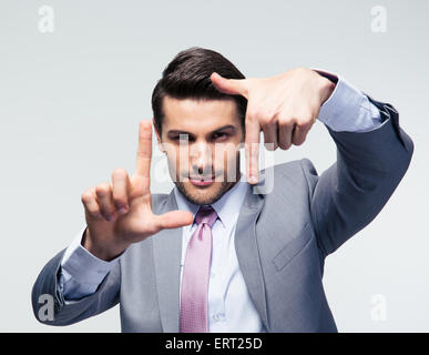 Businessman making frame gesture over gray background and looking at camera Stock Photo