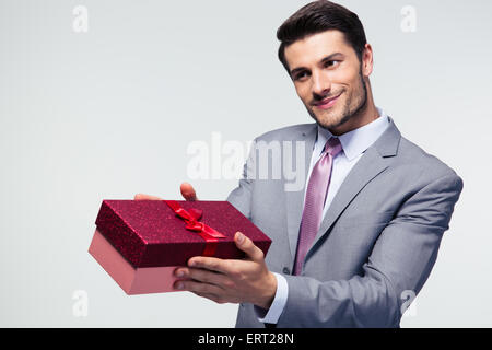 Businessman giving gift box to something over gray background Stock Photo