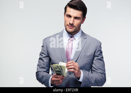 Handsome businessman counting US dollars over gray background and looking at camera Stock Photo