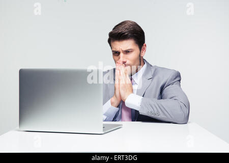 Businessman sitting at the table and praying over gray background Stock Photo