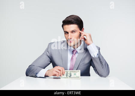 Happy businessman sitting at the table and holding us dollar bills over gray background Stock Photo