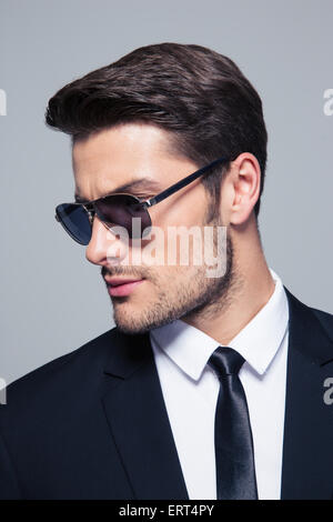 Young businessman in sunglasses looking away over gray background Stock Photo