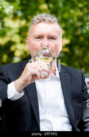 man in a suit holding a glass of wine Stock Photo