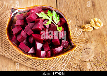 Beetroot (beet) chopped with parsley in bowl over rustic wooden table Stock Photo