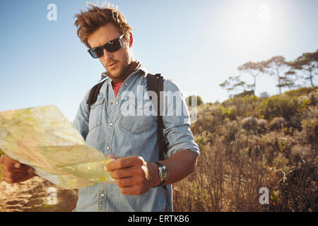 Shot of a handsome hiker using a map. Hiker using a map to navigate his hike on a summer day. Stock Photo