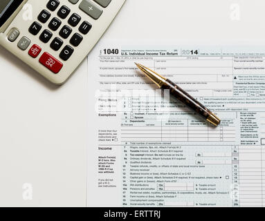 USA tax form 1040 for year 2014 with a pen and calculator illustrating completion of tax forms for the IRS Stock Photo