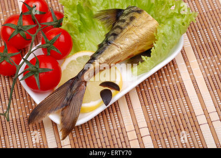 Composition from a smoked mackerel on a plate with vegetables Stock Photo
