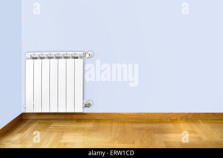 White heating radiator on blue wall and wooden parquet floor Stock Photo