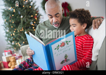 Mixed race grandfather reading to grandson at Christmas Stock Photo