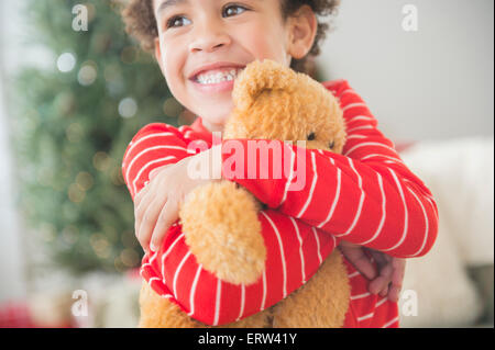 Mixed race boy hugging teddy bear at Christmas Stock Photo