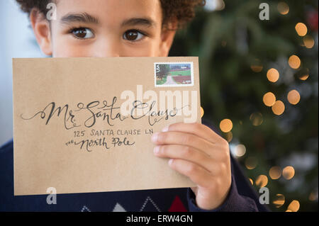 Mixed race boy holding letter to Santa for Christmas Stock Photo