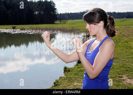 young woman standing by a lake and in boxer pose Stock Photo