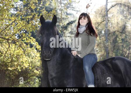 woman rides Frisian horse Stock Photo