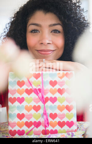 Mixed race woman holding wrapped gift Stock Photo