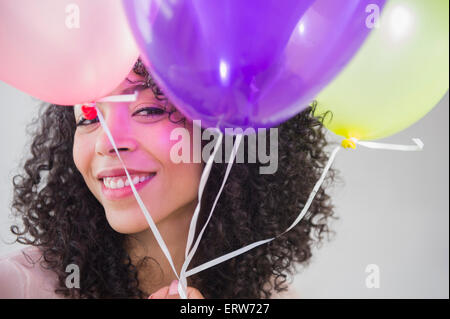 Mixed race woman holding bunch of balloons Stock Photo